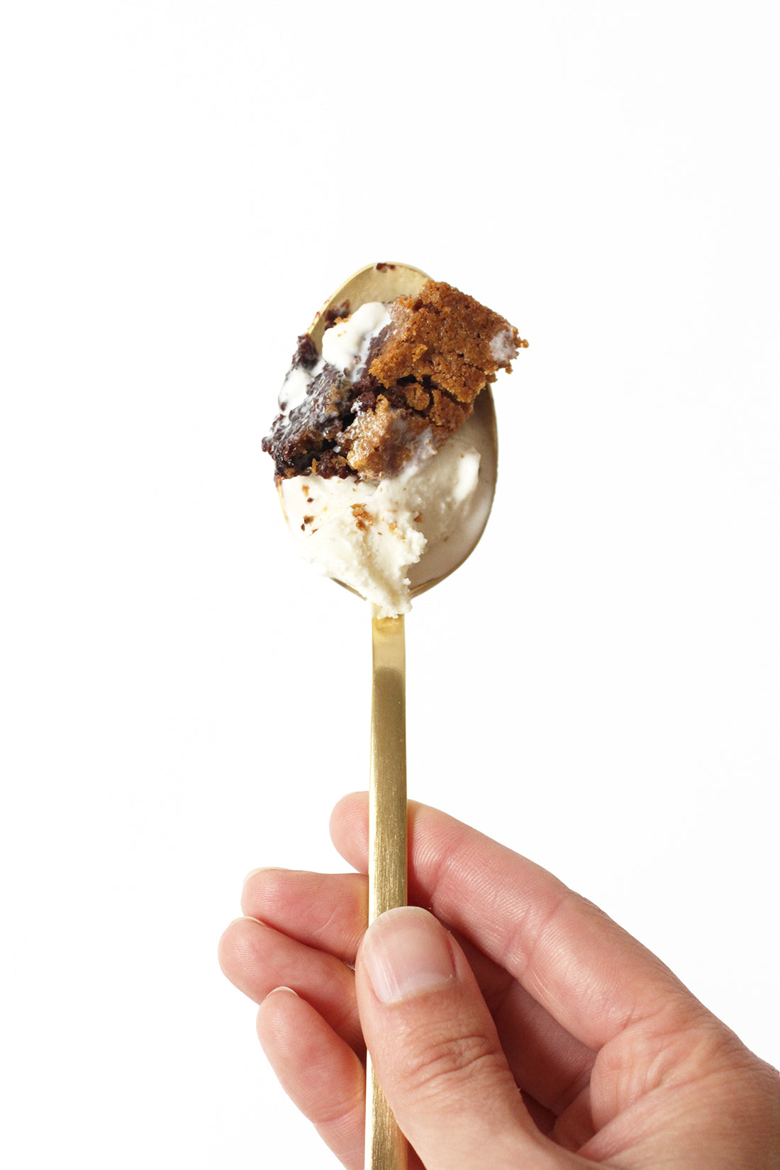 A bite of Miss Jones Baking Co Chocolate Chip Brownie Skillet held up on a golden spoon