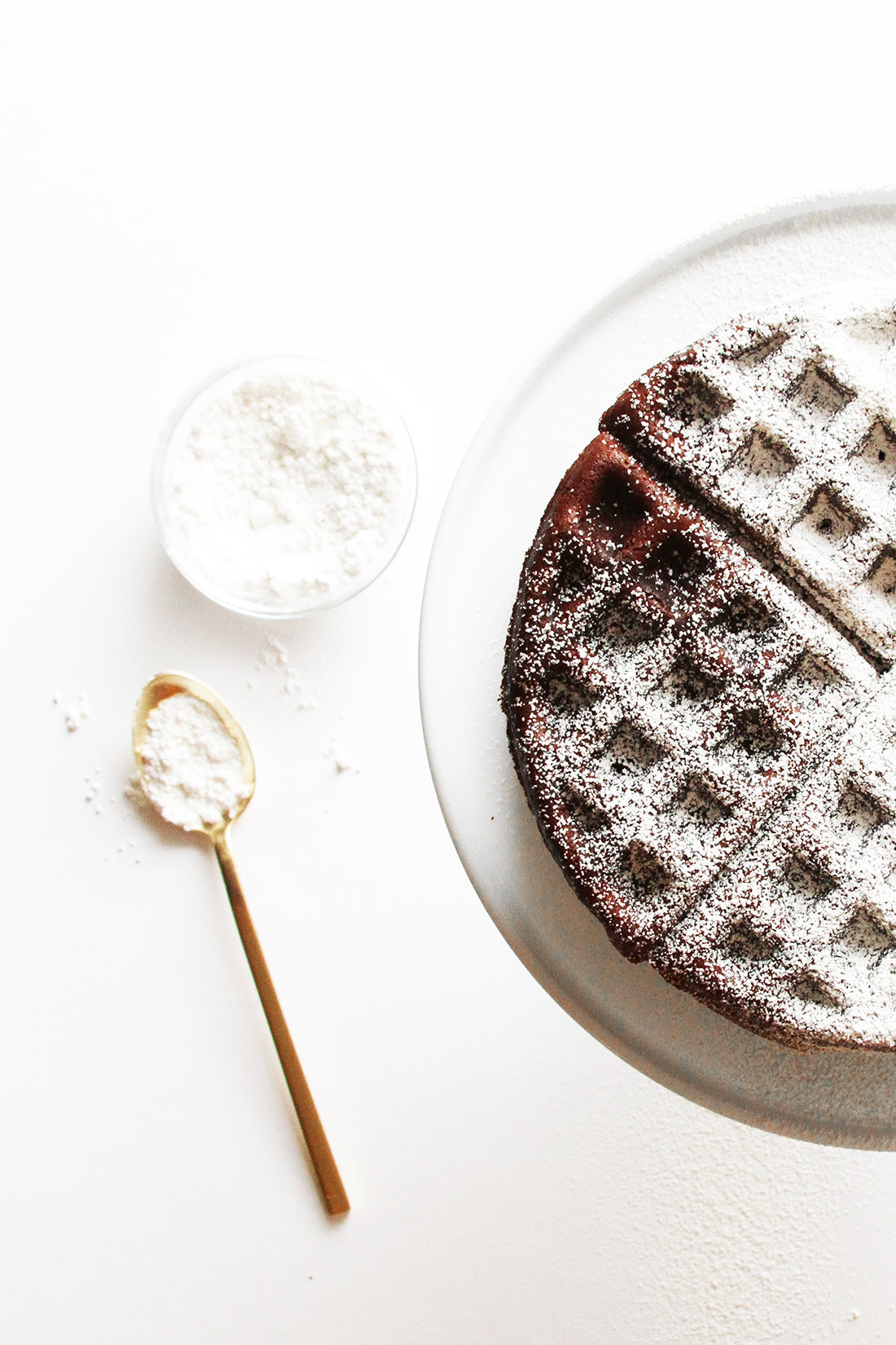 Half of Miss Jones Baking Co Chocolate Cake Waffles on a plate next to a spoon