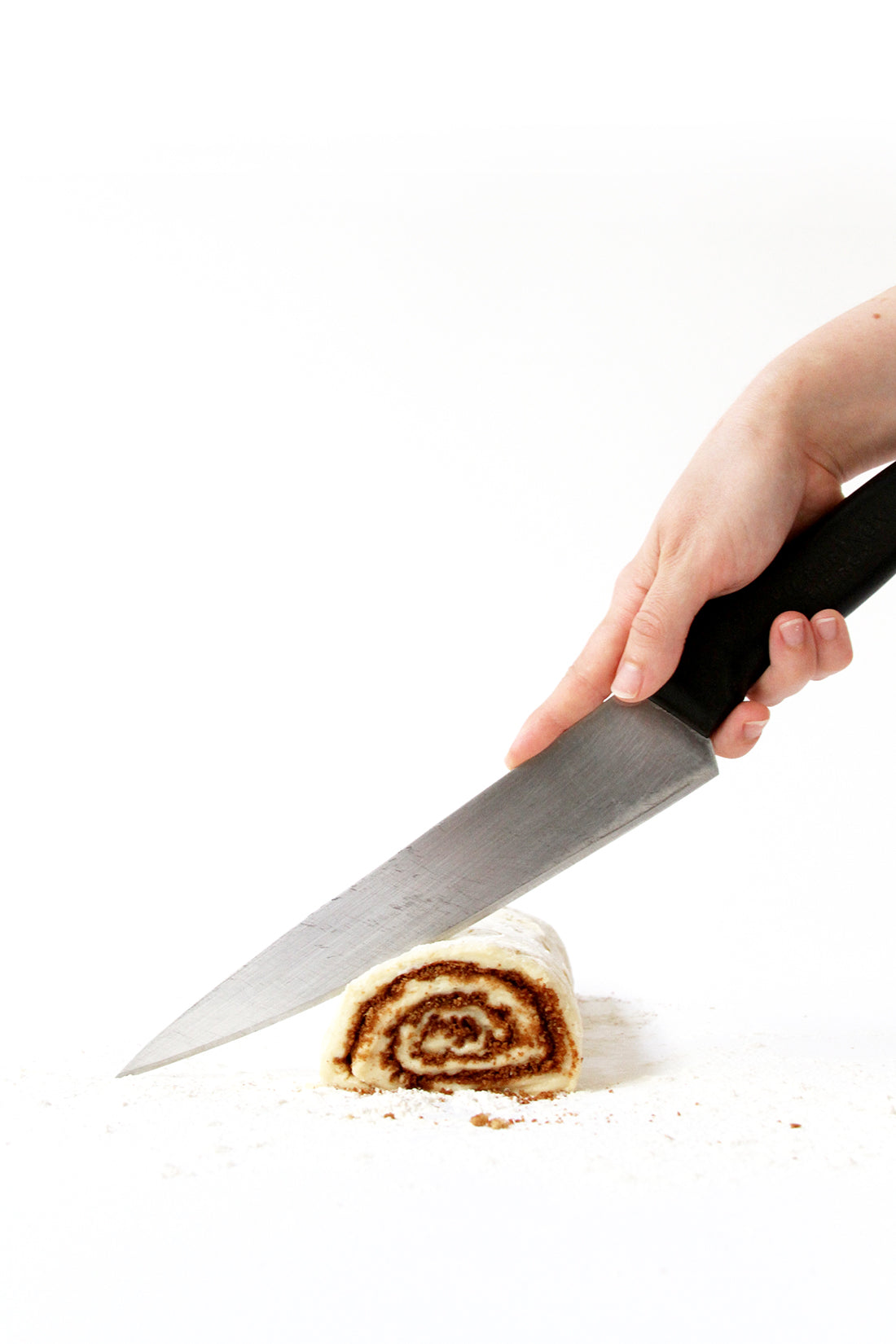Image of Miss Jones Baking Co Cake Mix Cinnamon Rolls in a log being cut by a knife into pieces
