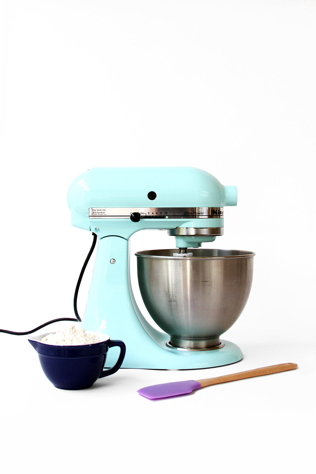 Image of side of blue kitchen aid next to spatula and ingredients for Miss Jones Baking Co Cake Mix Cinnamon Rolls