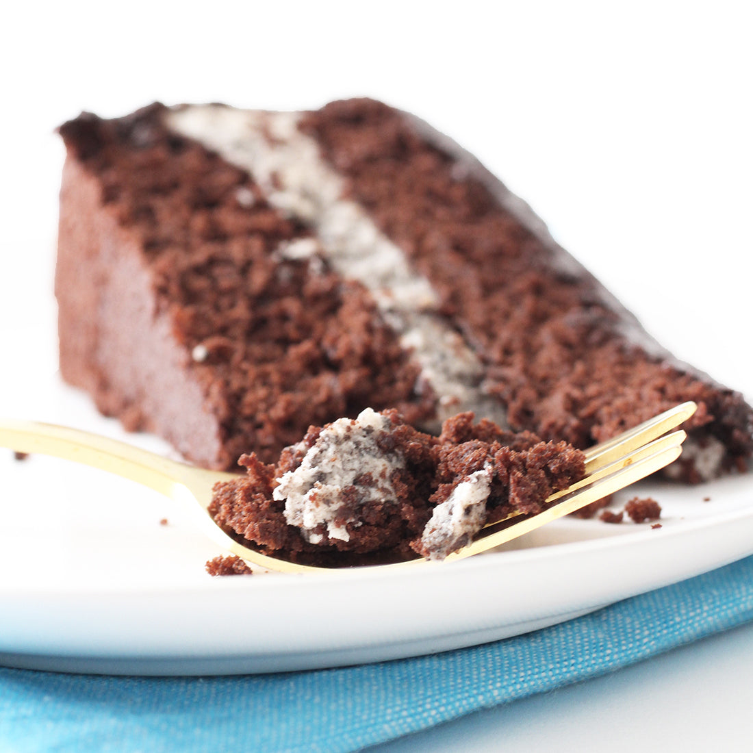 Close up image of a bite of Miss Jones Baking Co Minty Cookie Crunch Cake in front of a slice of Miss Jones Baking Co Minty Cookie Crunch Cake