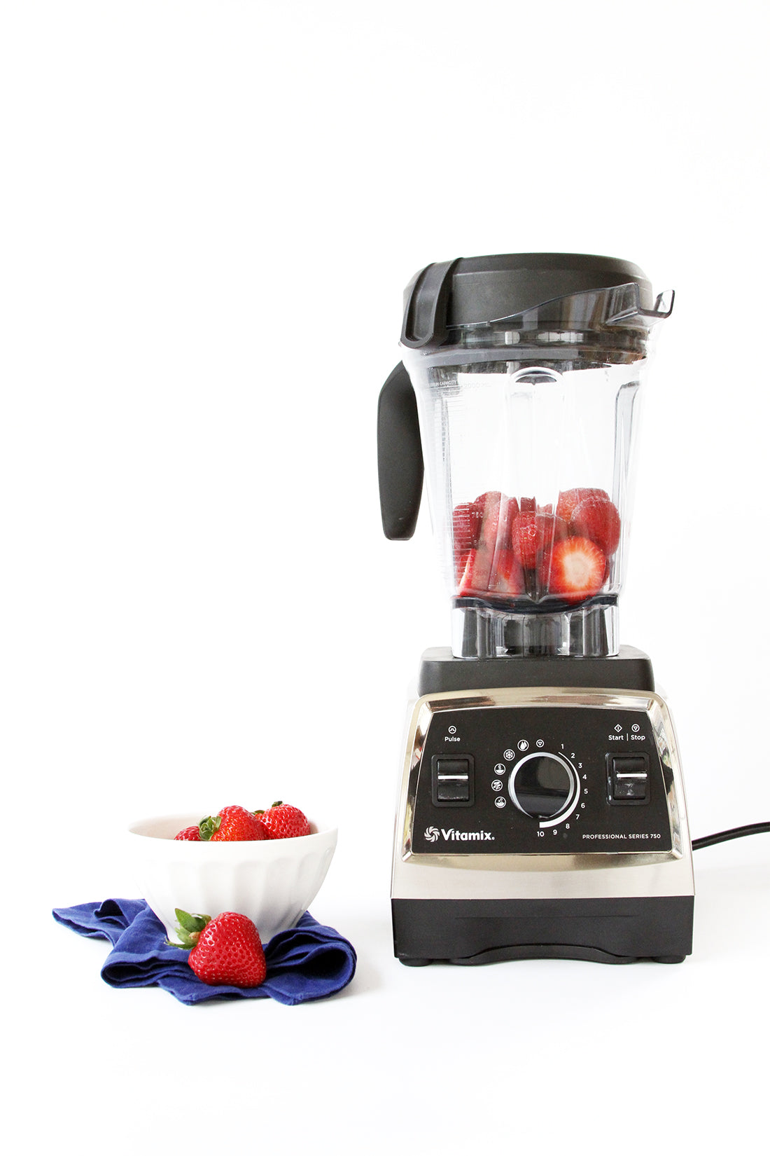 Image of strawberries in a blender next to a bowl of strawberries used for Miss Jones Baking Co Firecracker Pops recipe