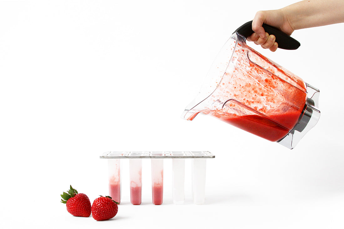 Image of a hand pouring blended strawberries from a blender into popsicle molds for Miss Jones Baking Co Firecracker Pops