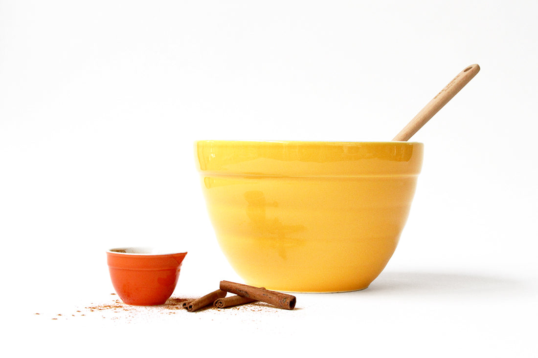 A large yellow mixing bowl next to a small orange bowl and some cinnamon sticks used for Miss Jones Baking Co Classic Hummingbird Cake