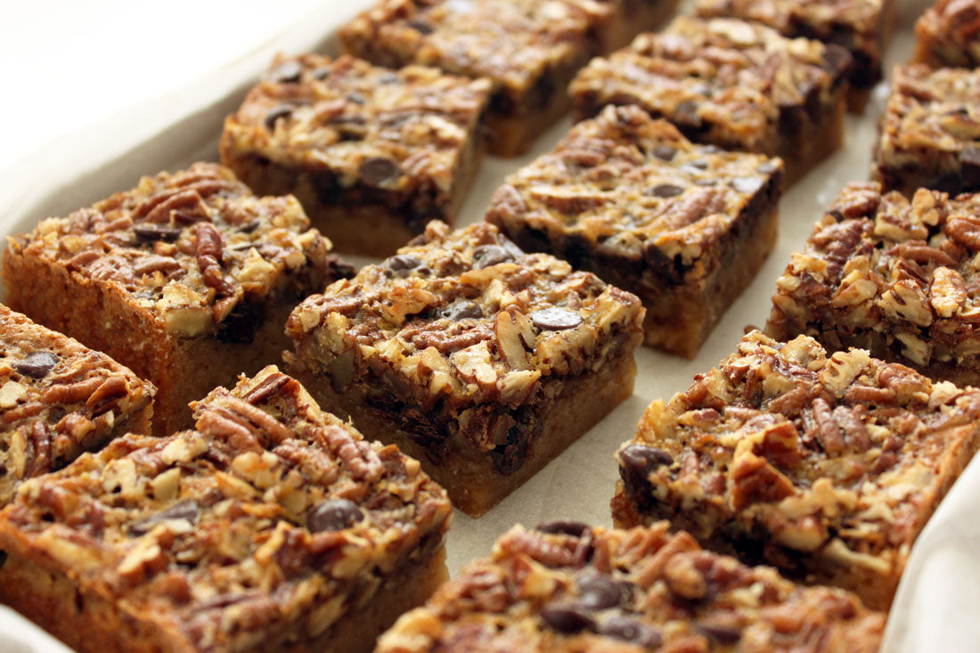 Close up image of Miss Jones Baking Co Chocolate Pecan Pie Butter Bars on a baking sheet lined with parchment paper