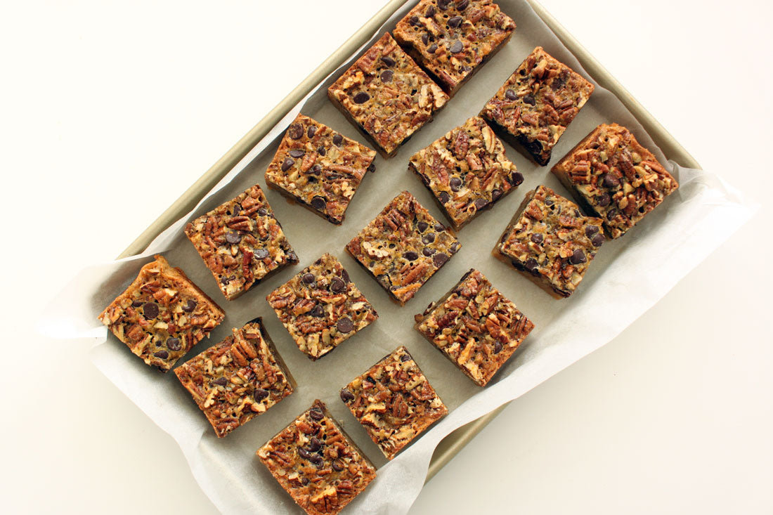 Fifteen Miss Jones Baking Co Chocolate Pecan Pie Butter Bars on a baking sheet lined with parchment paper