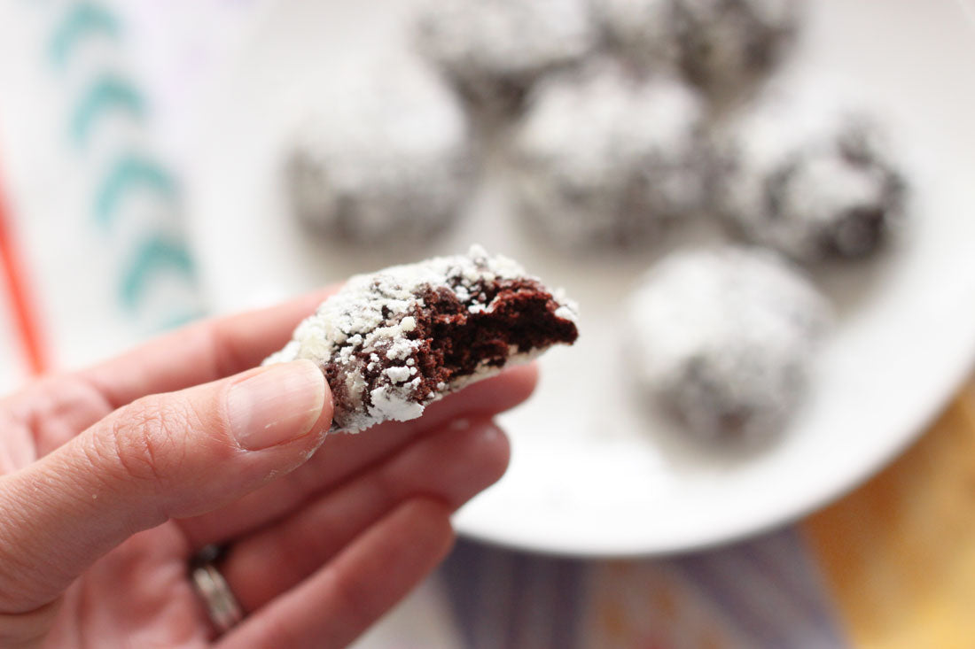 Hand holding a Miss Jones Baking Co Chocolate Cake Mix Crinkle Cookie with a bite out of it