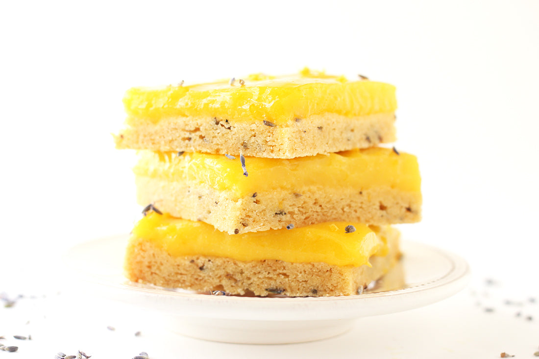 Image of the side of a stack of three Miss Jones Baking Co Lavender Lemon Bars on a plate