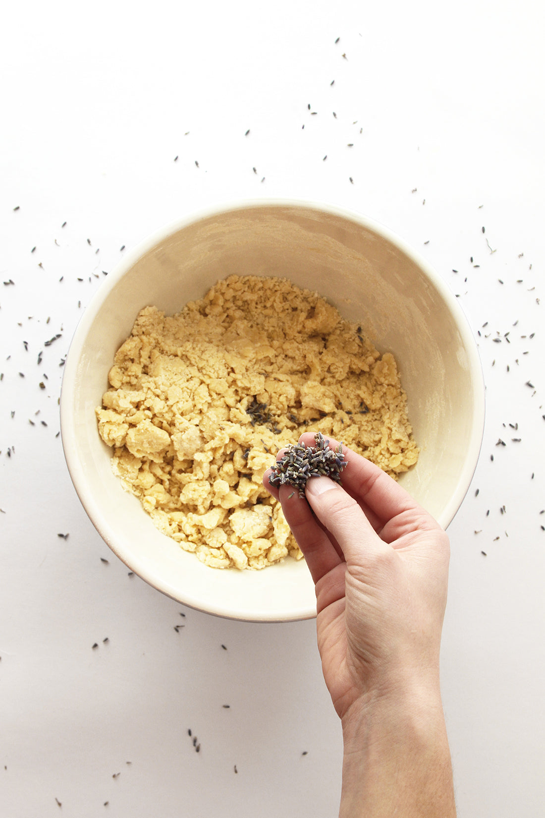 Image of a hand putting lavender into bowl with crust crumbs for Miss Jones Baking Co Lavender Lemon Bars recipe