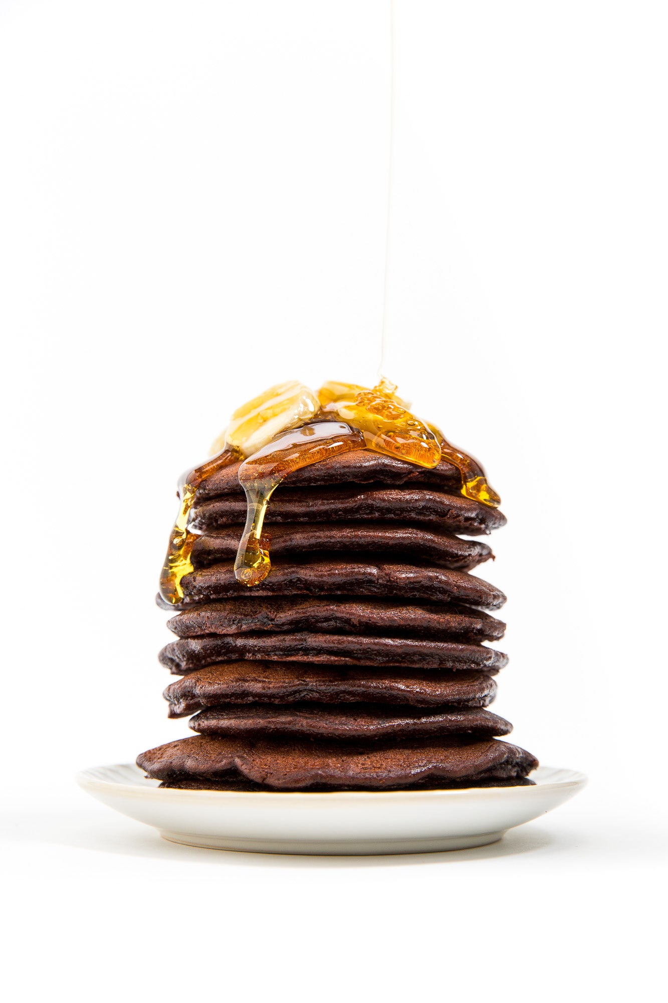 Stack of Miss Jones Baking Co Double Chocolate Stout Pancakes with melted butter and slices of banana on top