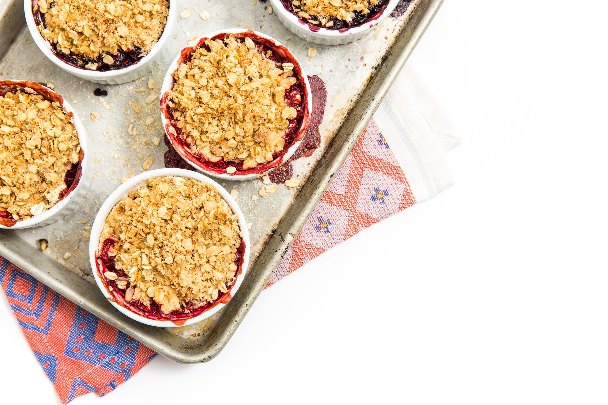 Image from above of Miss Jones Baking Co Mini Berry Crumbles in ramekins on a baking tray