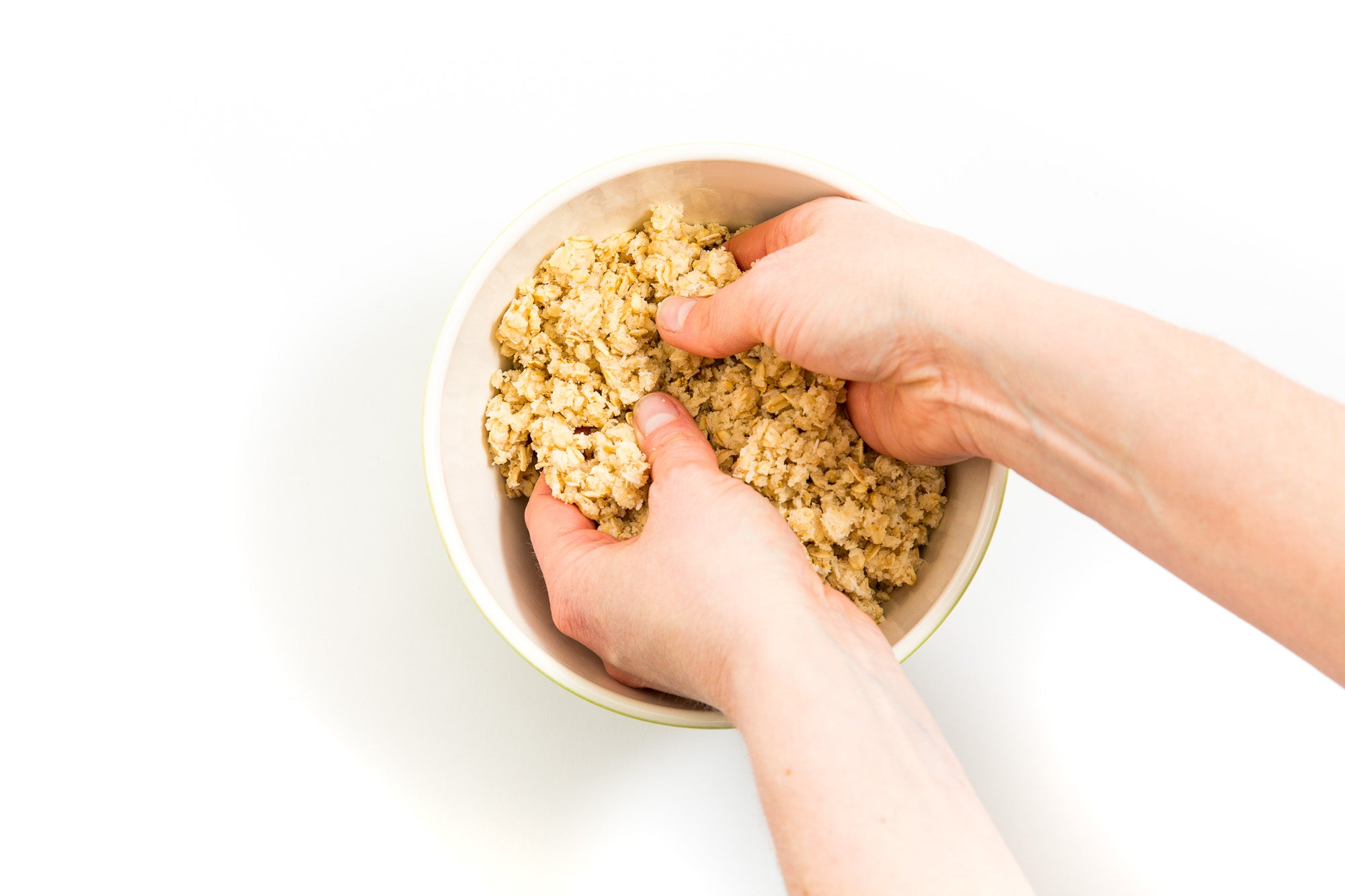 Image from above of hands mixing dough in a bowl for Miss Jones Baking Co Mini Berry Crumbles recipe