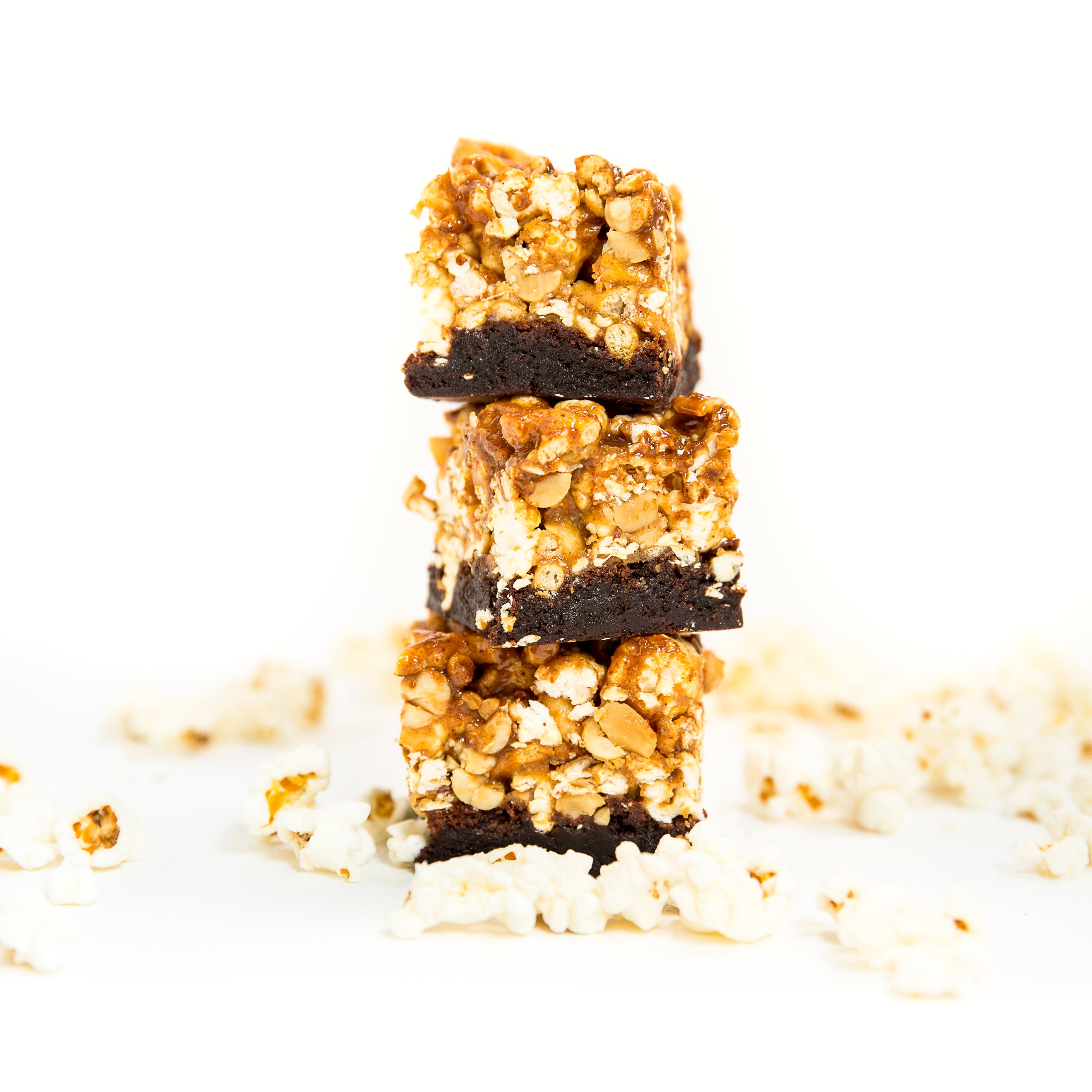 Image of three Miss Jones Baking Co Popcorn Brownies stacked and surrounded by popcorn