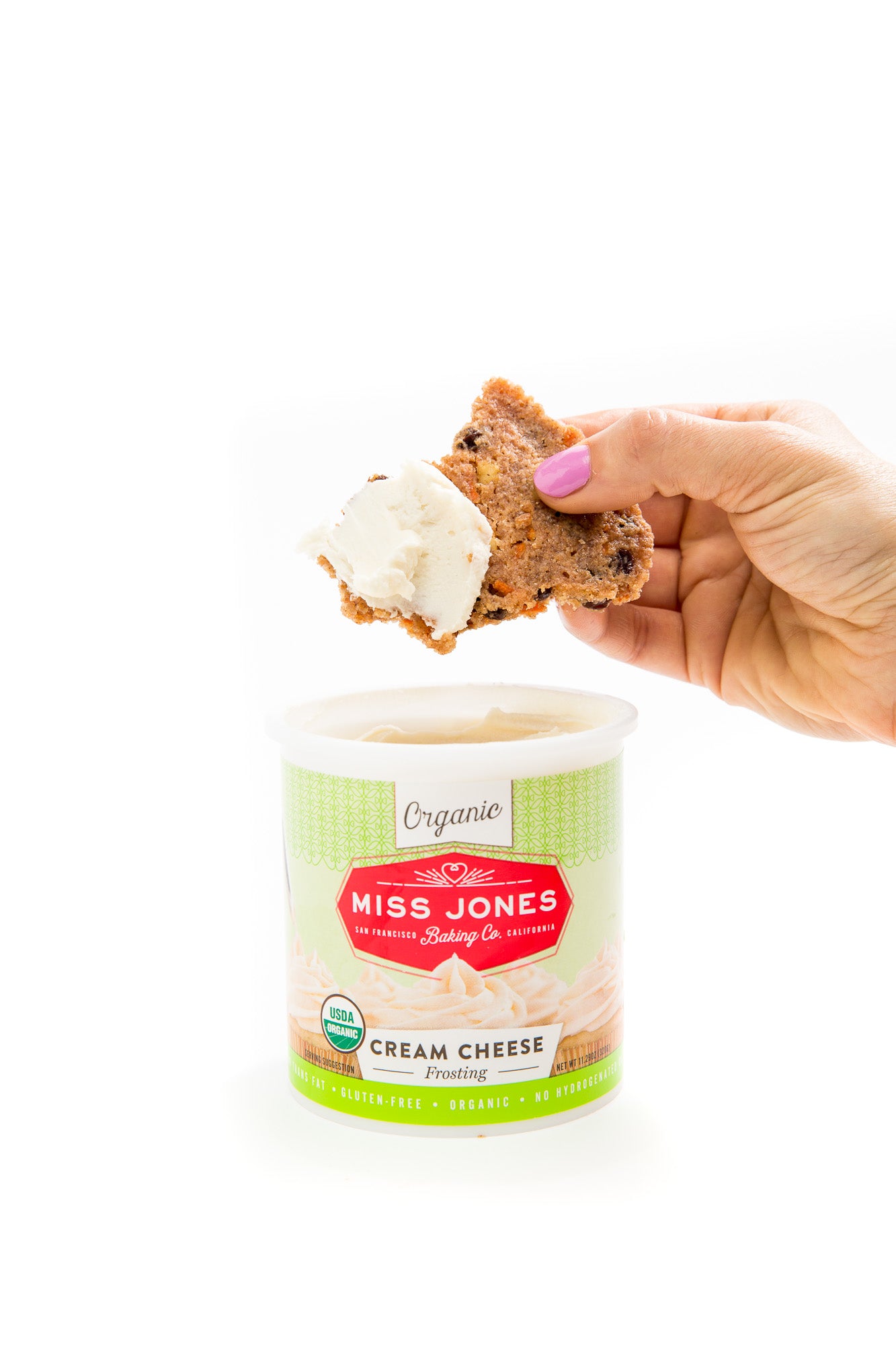 Image of Miss Jones Baking Co Carrot Cake Bark being dipped into a jar of Miss Jones Cream Cheese Frosting