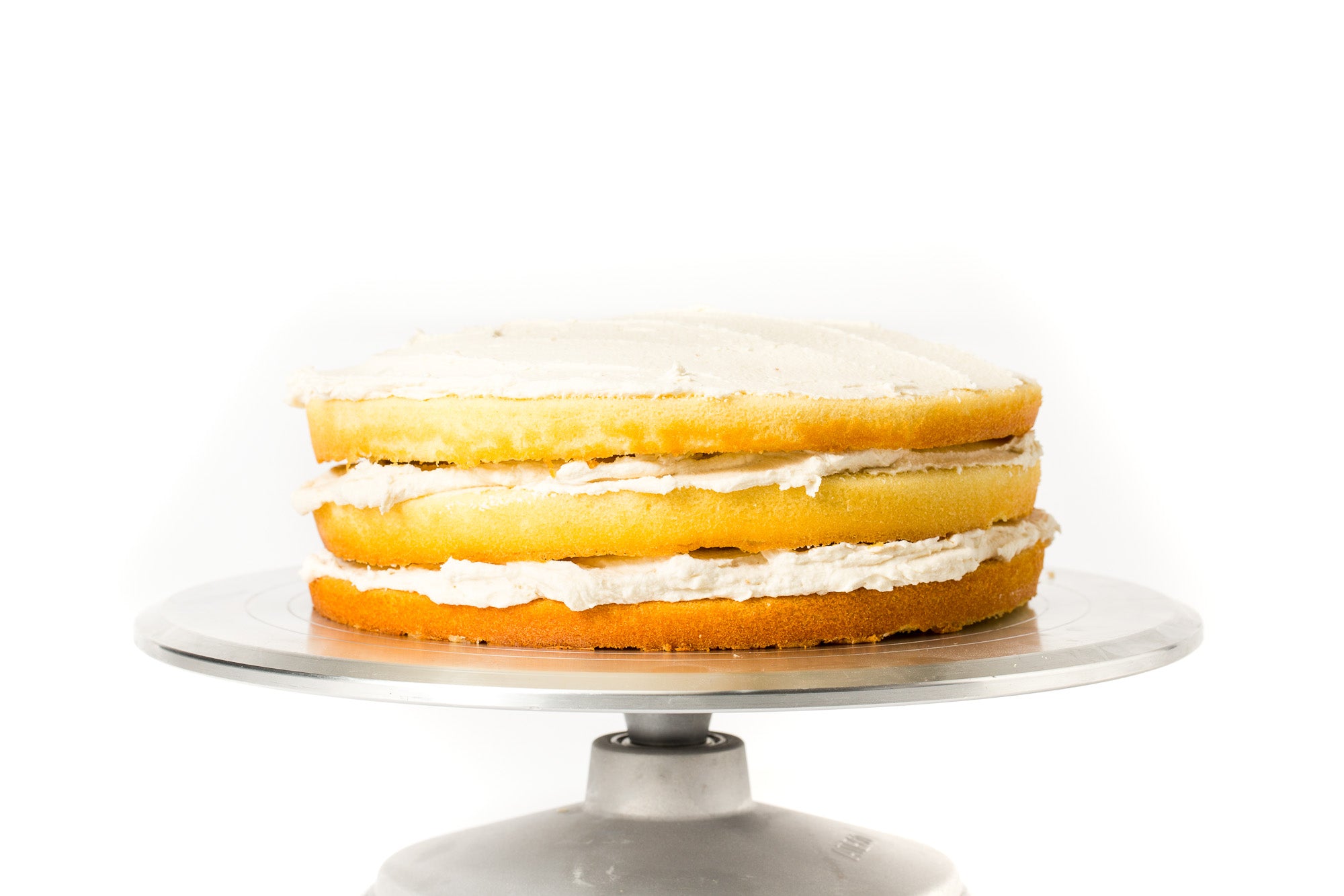 Image of three layers of stacked cakes and frosting for Miss Jones Baking Co Floral Bloom Layer Cake on a cake stand