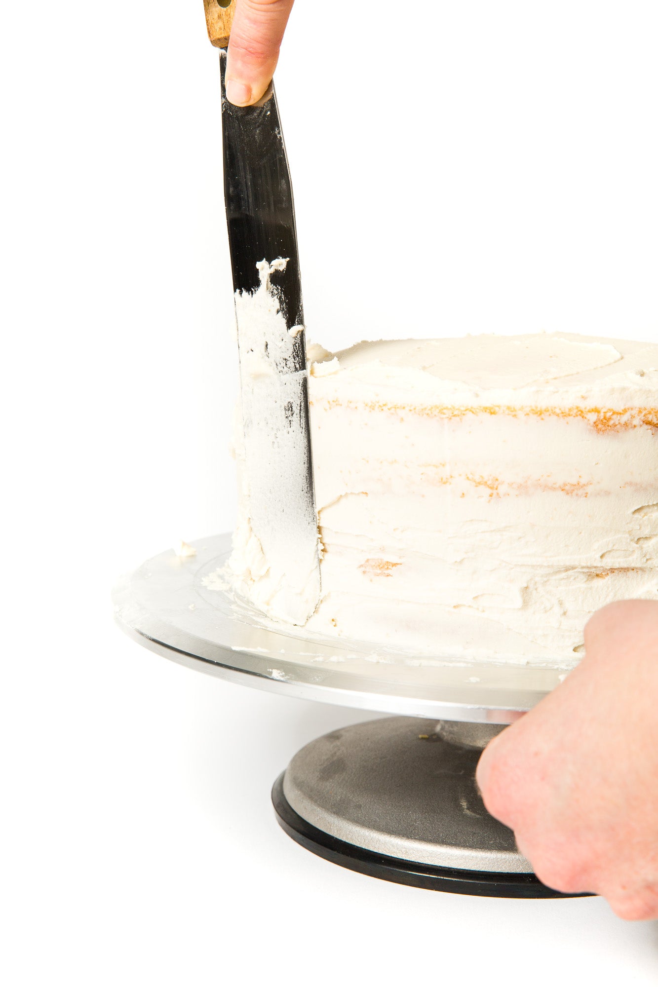 Image of part of Miss Jones Baking Co Floral Bloom Layer Cake being frosted on a cake stand