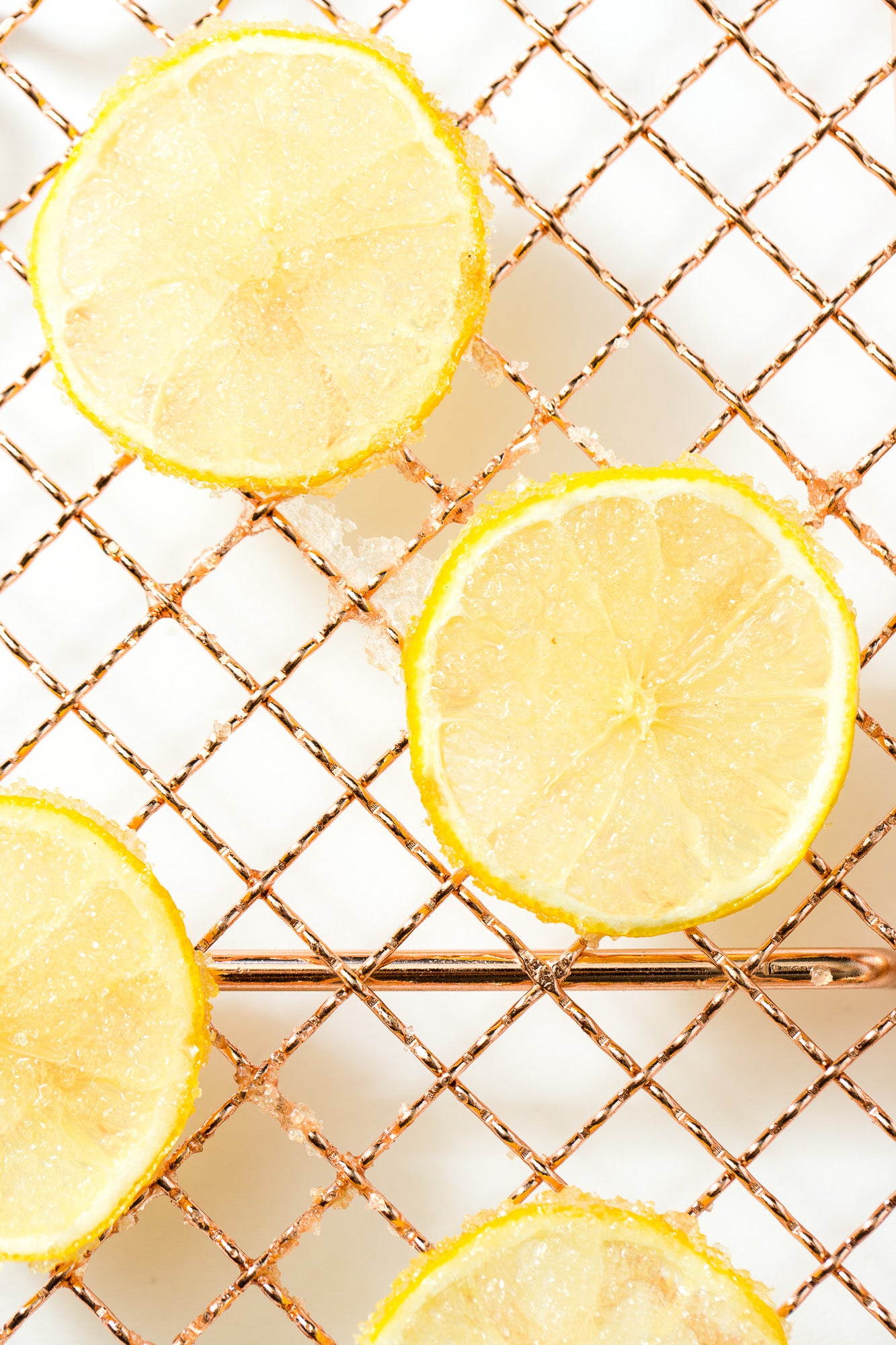 A close up image of thinly sliced candied lemons on a baking rack for Miss Jones Baking Co Lemonade Donuts