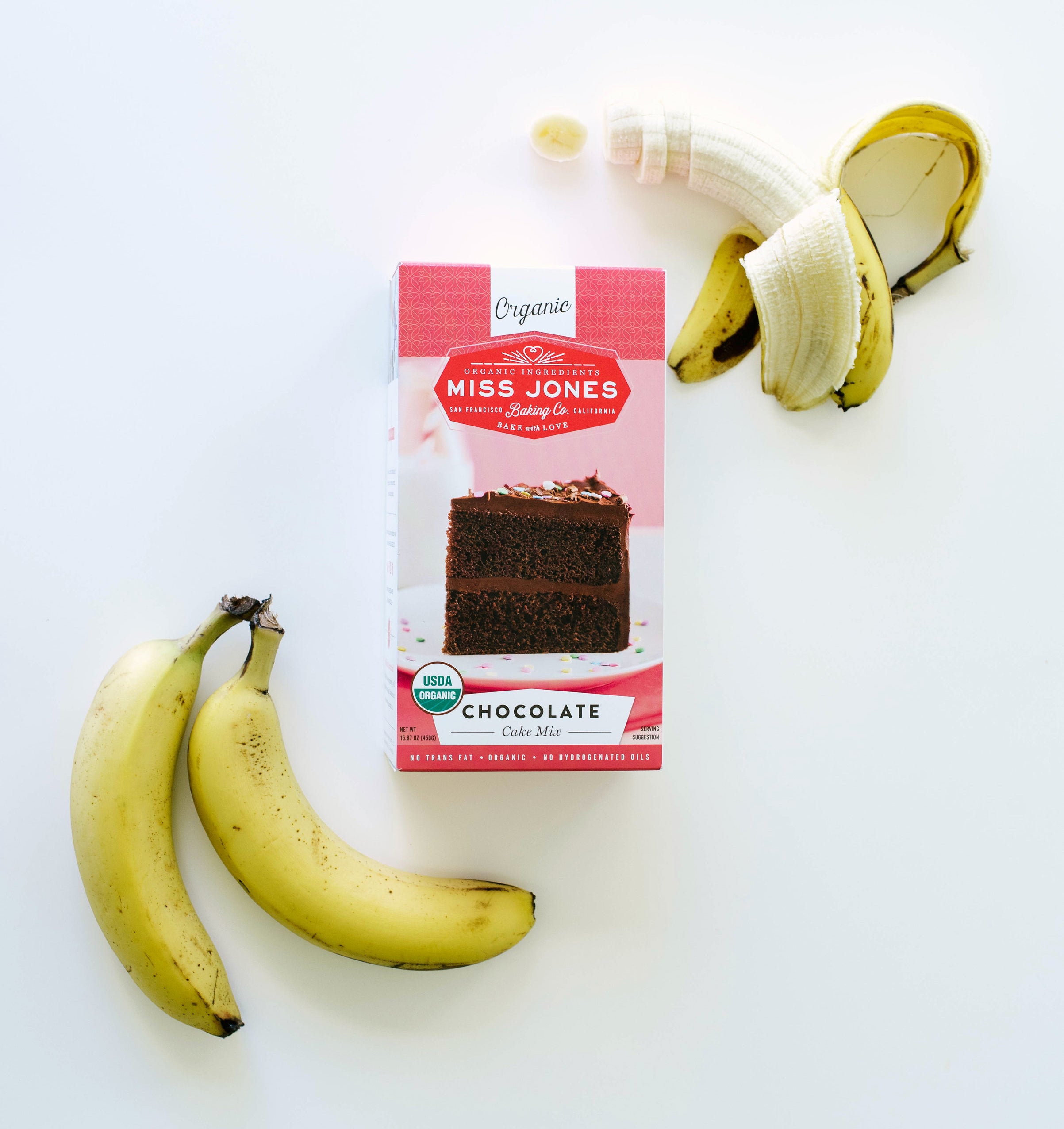 A box of Miss Jones Chocolate Cake Mix surrounded by three bananas used for Miss Jones Baking Co Chocolate Cake Batter Peanut Butter Nice Cream recipe