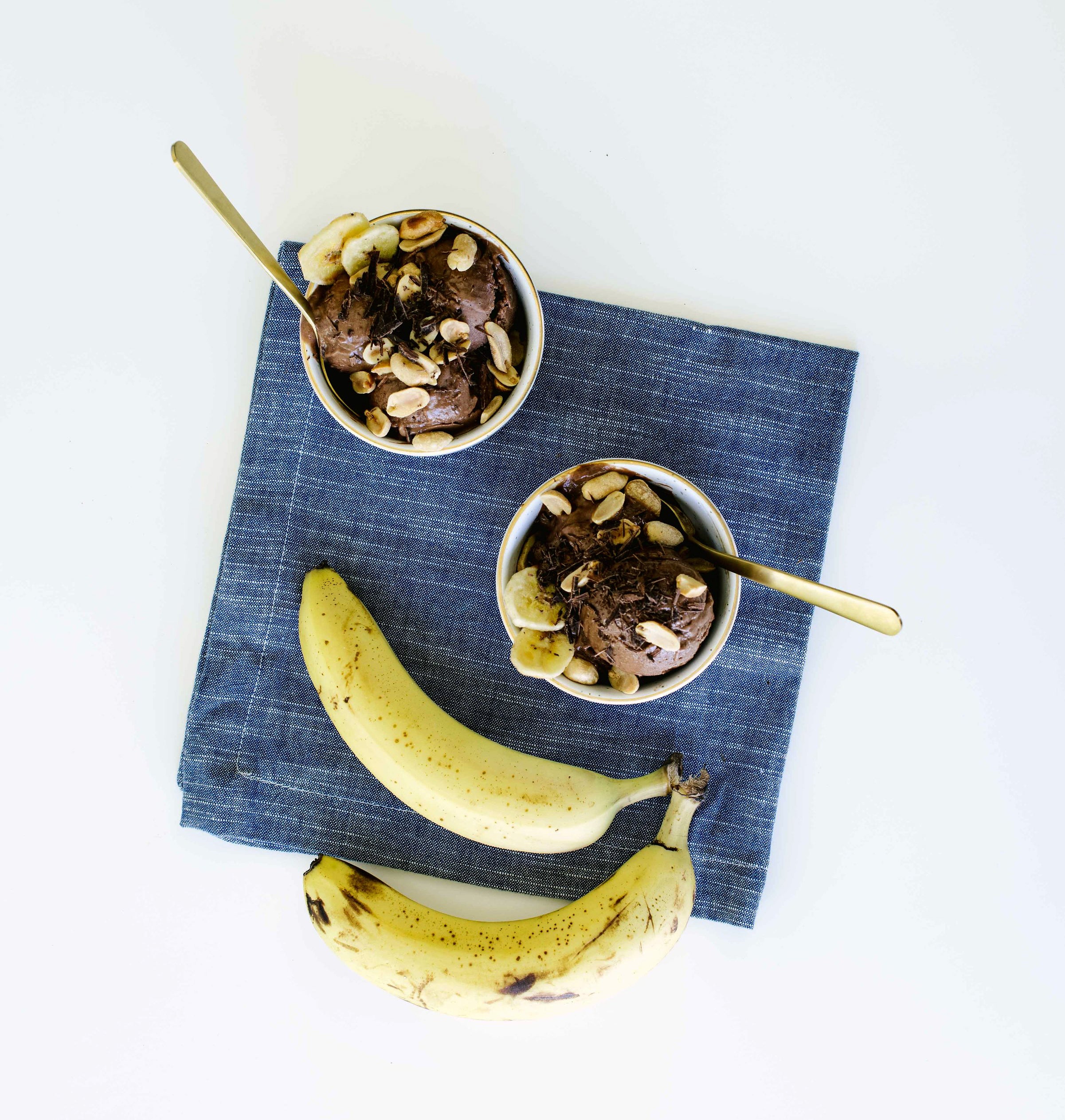 Two bowls of Miss Jones Baking Co Chocolate Cake Batter Peanut Butter Nice Cream next to two bananas