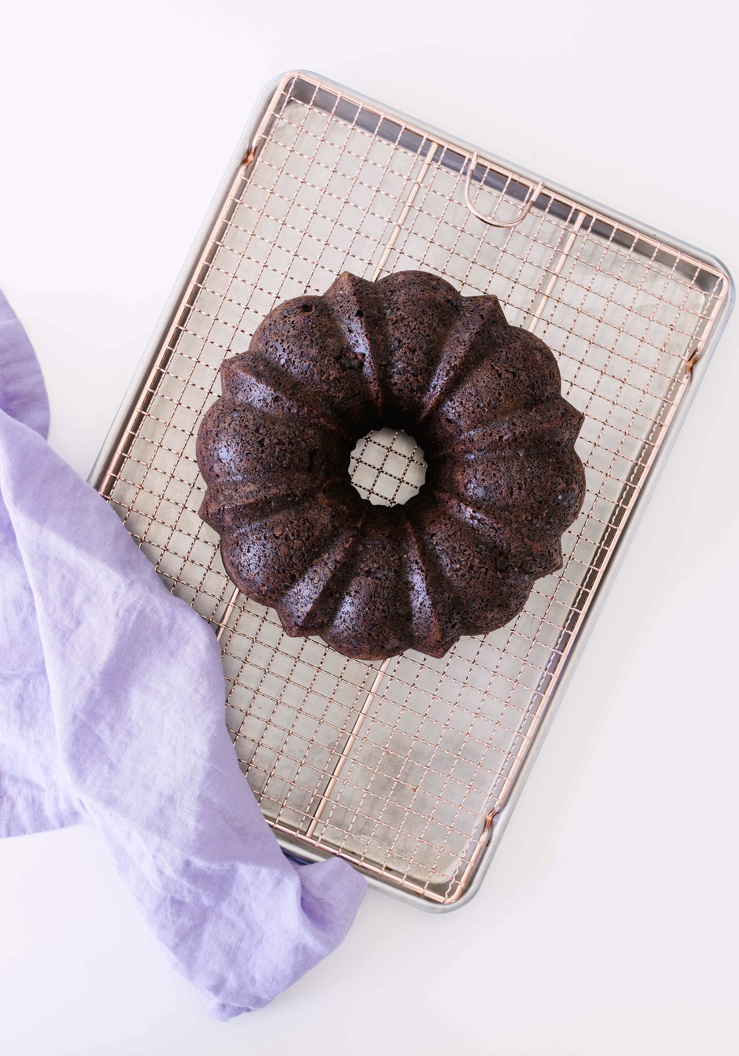 Top of Miss Jones Baking Co Dark Chocolate Coconut Bundt Cake on a baking sheet next to a purple towel