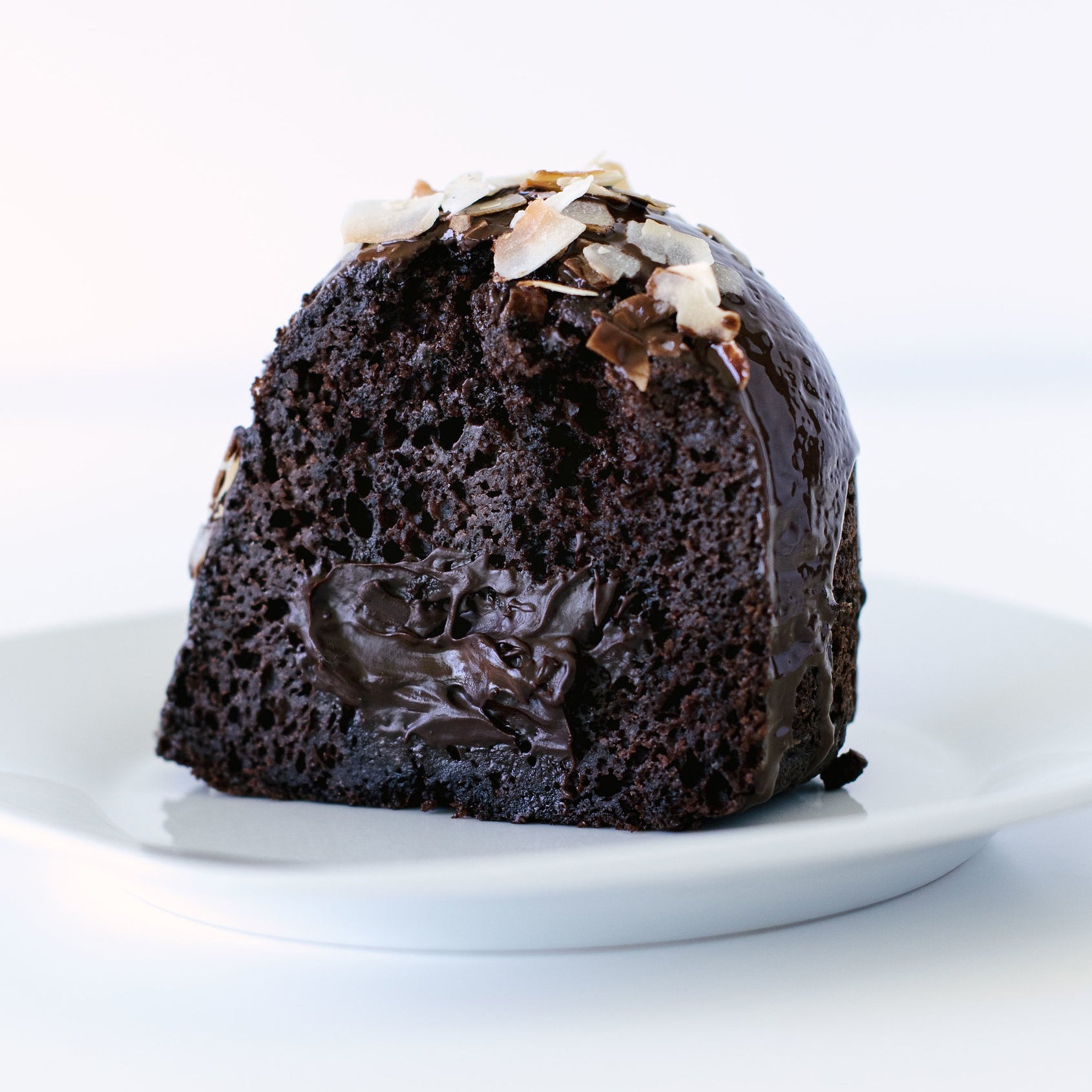 Close up of inside of a slice of Miss Jones Baking Co Dark Chocolate Coconut Bundt Cake on a white plate