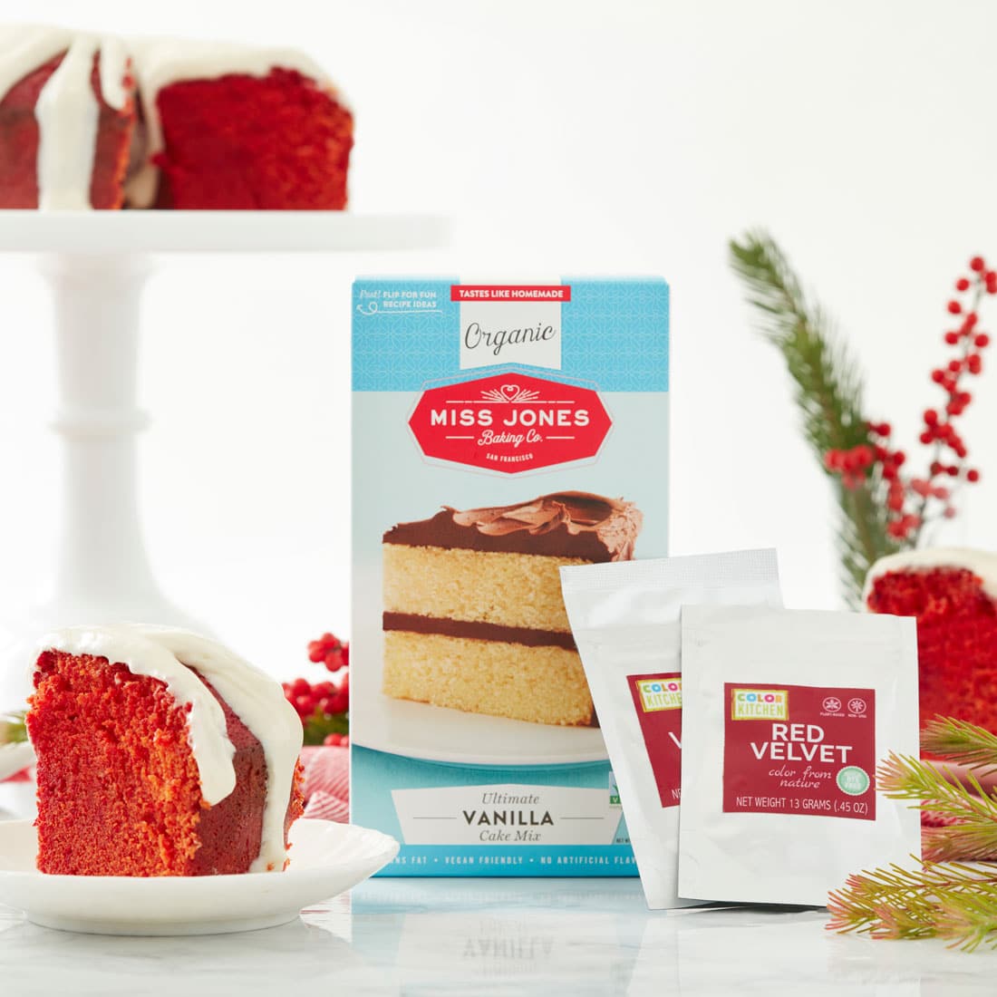 Image of Miss Jones Baking Co's Red Velvet Bundt Cake and Cream Cheese Glaze slice and Miss Jones Baking Co Vanilla Organic Cake Mix in the background