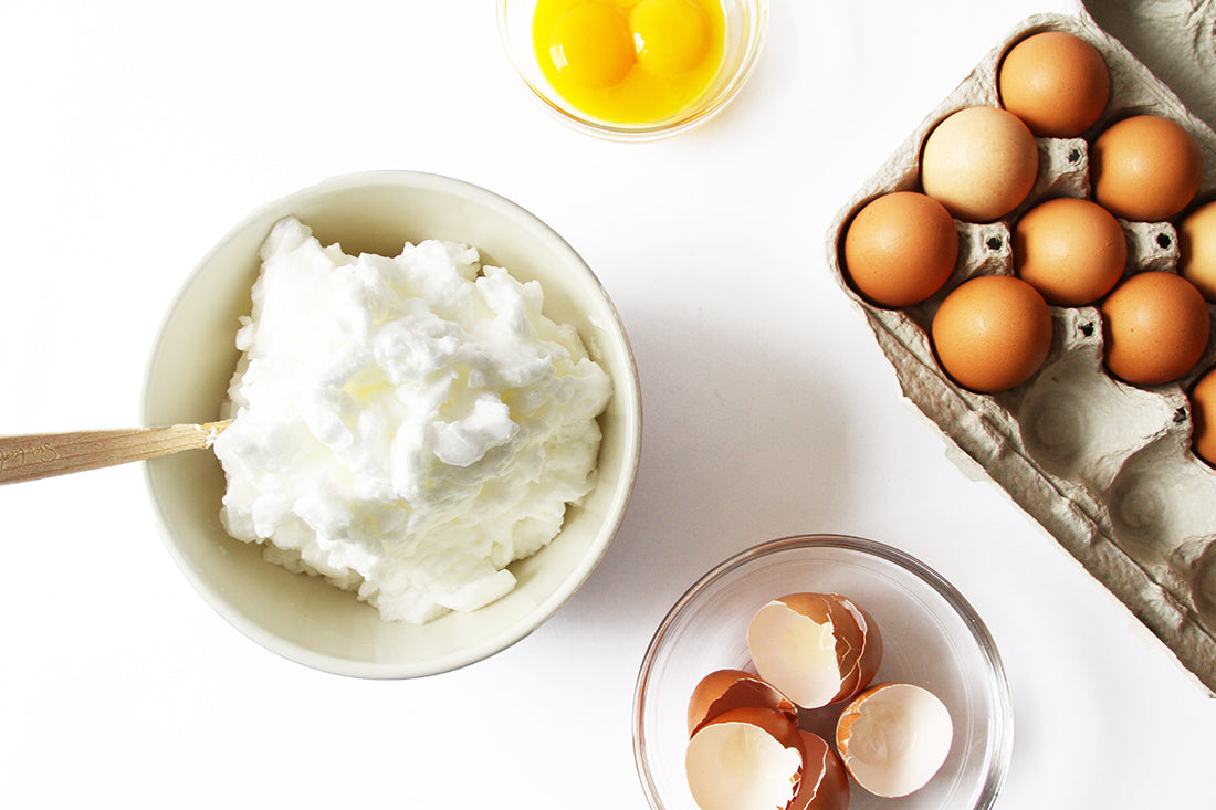 Image from above of a bowl of whipped cream next to a bowl of egg yolks, a bowl of egg shells and a carton of eggs for Miss Jones Baking Co Marmalade Madeleines