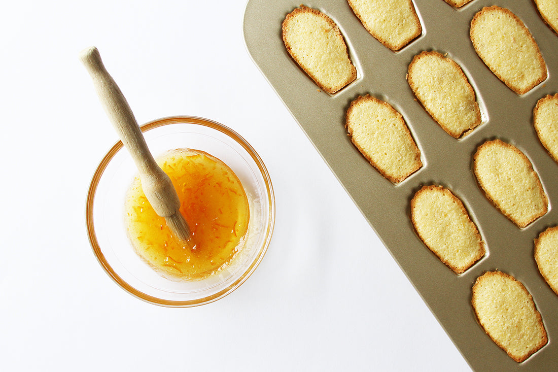 Image of part of a tray of Madeleines in a baking mold next to a bowl of marmalade for Miss Jones Baking Co Marmalade Madeleines