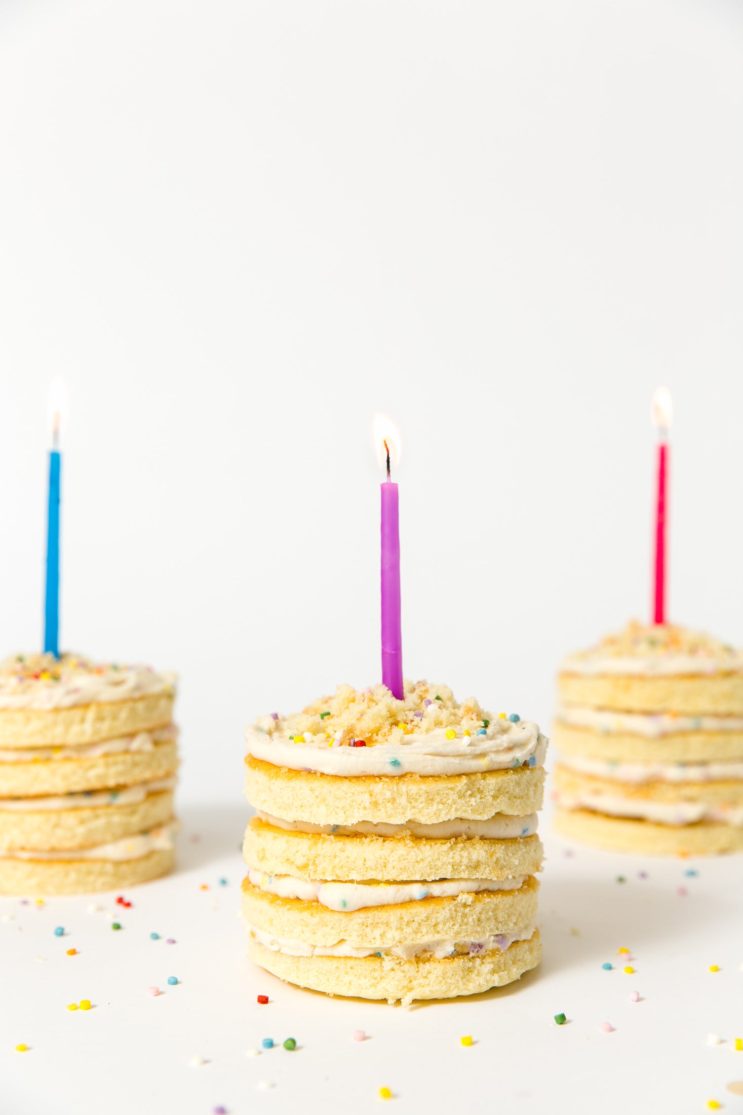 Image of side of three Miss Jones Baking Co Confetti Pop Mini Cakes with candles