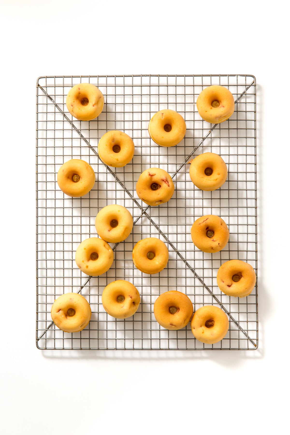 Image of sixteen donuts on a baking rack for Miss Jones Baking Co Strawberry Buttermilk Donuts recipe