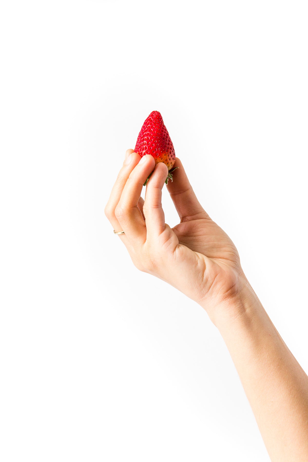 Image of a hand holding a strawberry for Miss Jones Baking Co Strawberry Buttermilk Donuts recipe