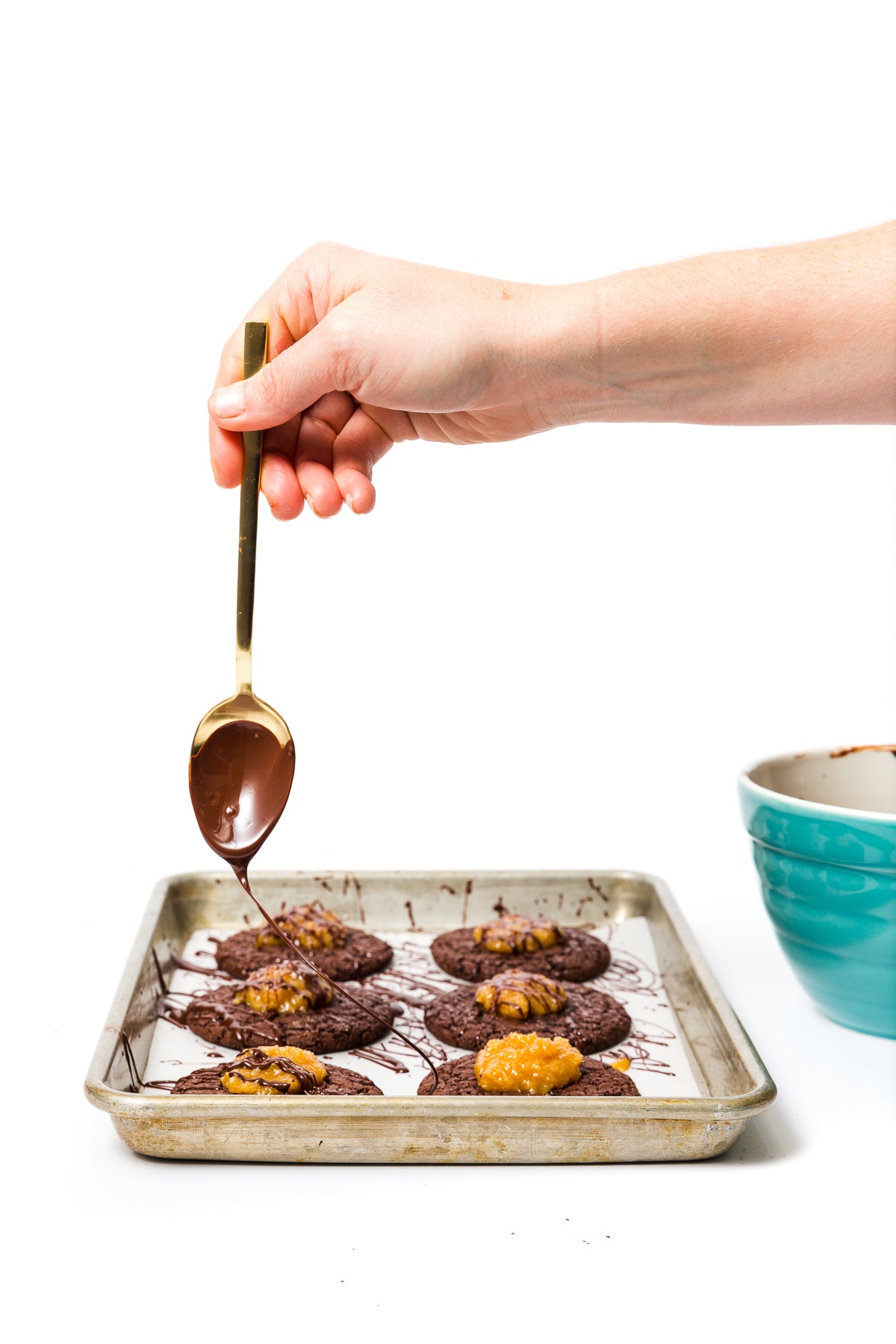 Image of side of six Miss Jones Baking Co Coconut Caramel Brownie Cookies with a hand drizzling chocolate on top