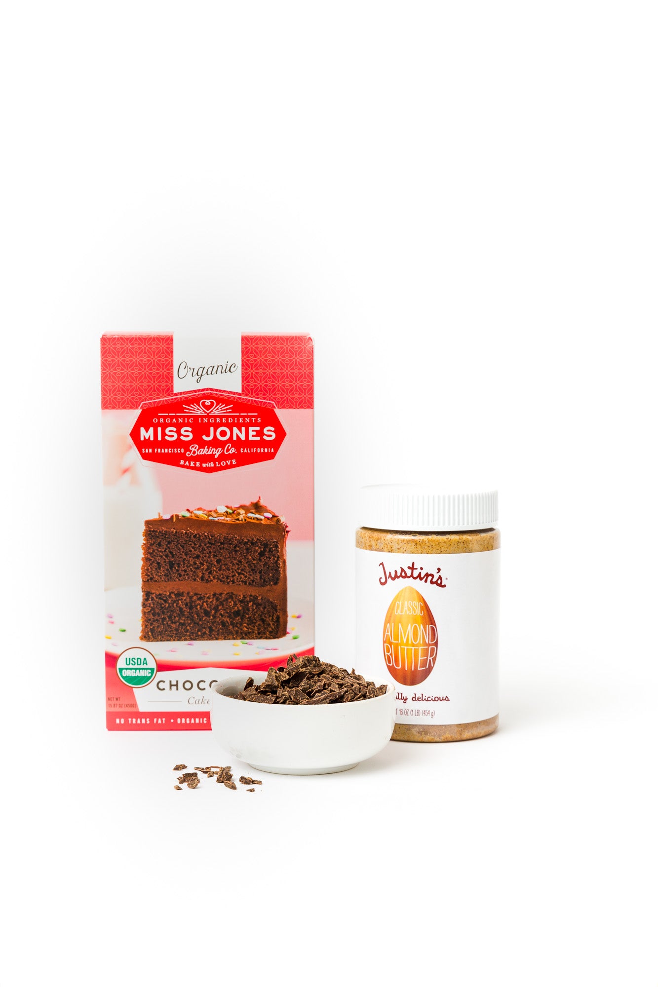 Image of Miss Jones Chocolate Cake Mix and Justin's Almond Butter behind a bowl of chocolate used for Miss Jones Baking Co Chocolate Almond Butter Bundt Cake recipe