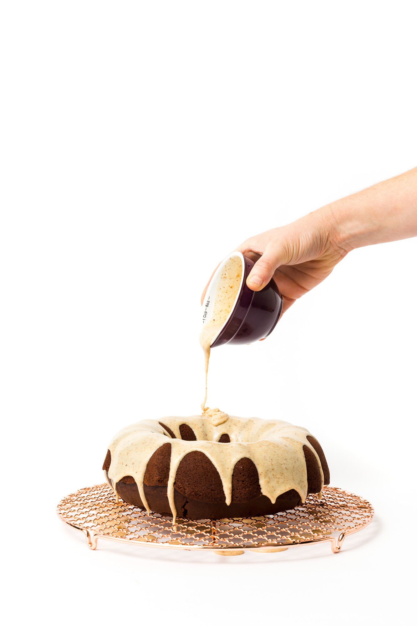 Image of frosting being poured over bundt cake on baking rack for Miss Jones Baking Co Chocolate Almond Butter Bundt Cake