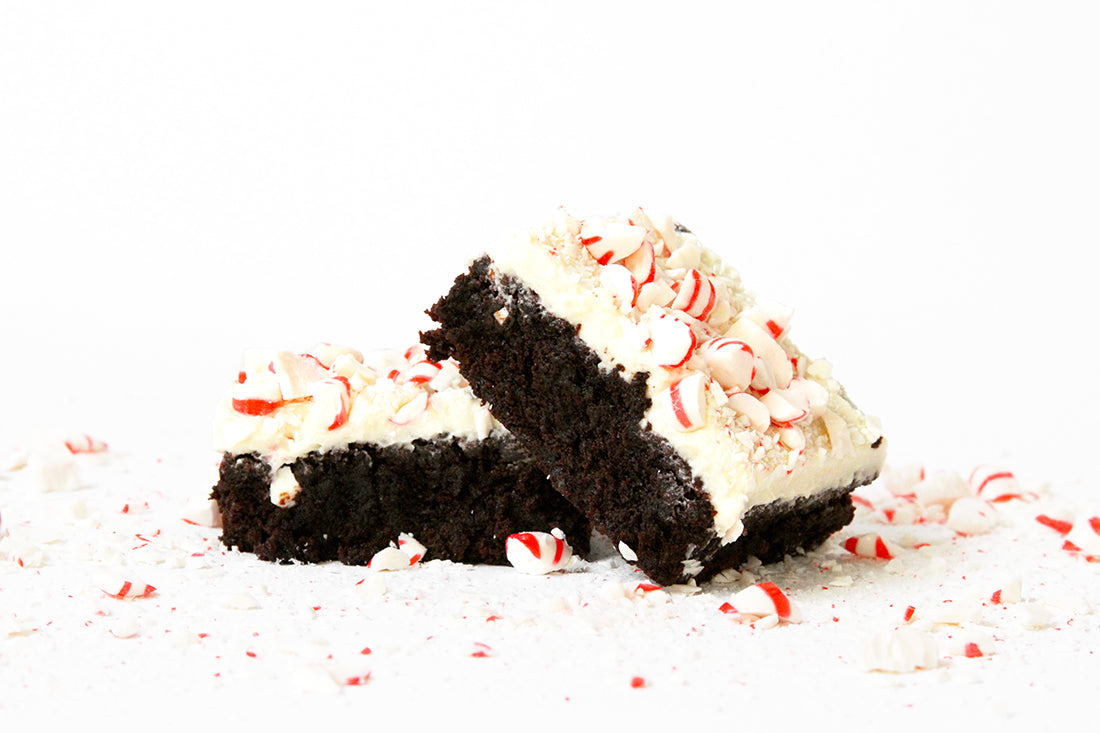 Image of two Miss Jones Baking Co Peppermint Bark Brownies stacked surrounded by crushed peppermint candies
