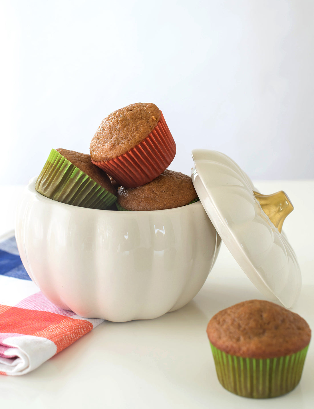 Image of the side of unfrosted Miss Jones Baking Co Pumpkin Spice Latte (PSL) Cupcakes in a ceramic white pumpkin jar