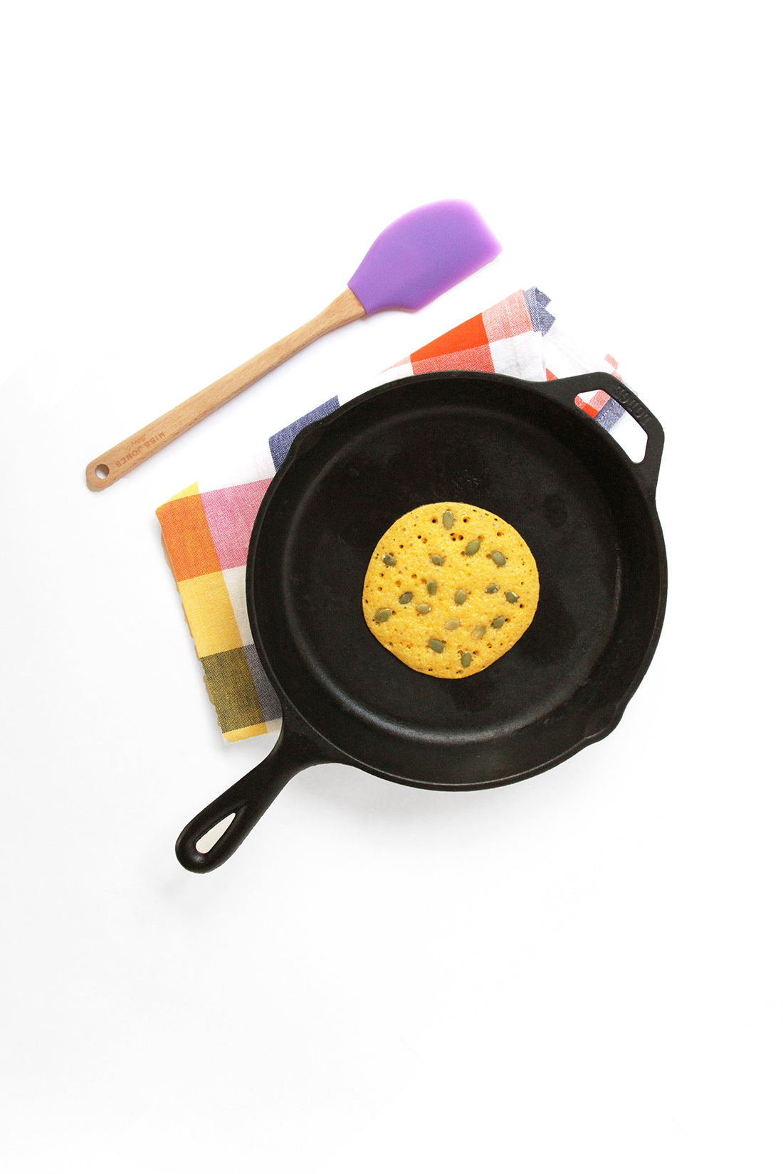 Image from above of a Miss Jones Baking Co Pumpkin Pancake on a skillet next to a purple spatula