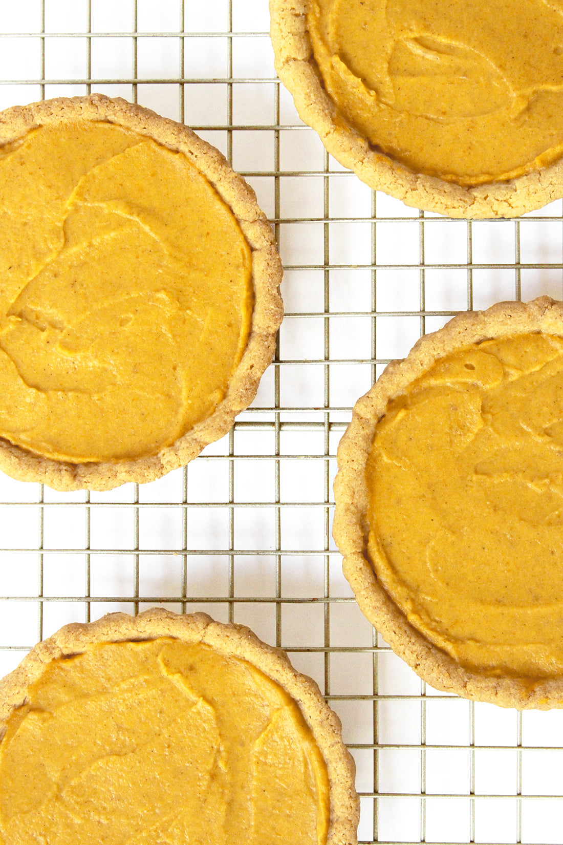 Image from above of four Miss Jones Baking Co Perfect Pumpkin Tartlets on a baking rack