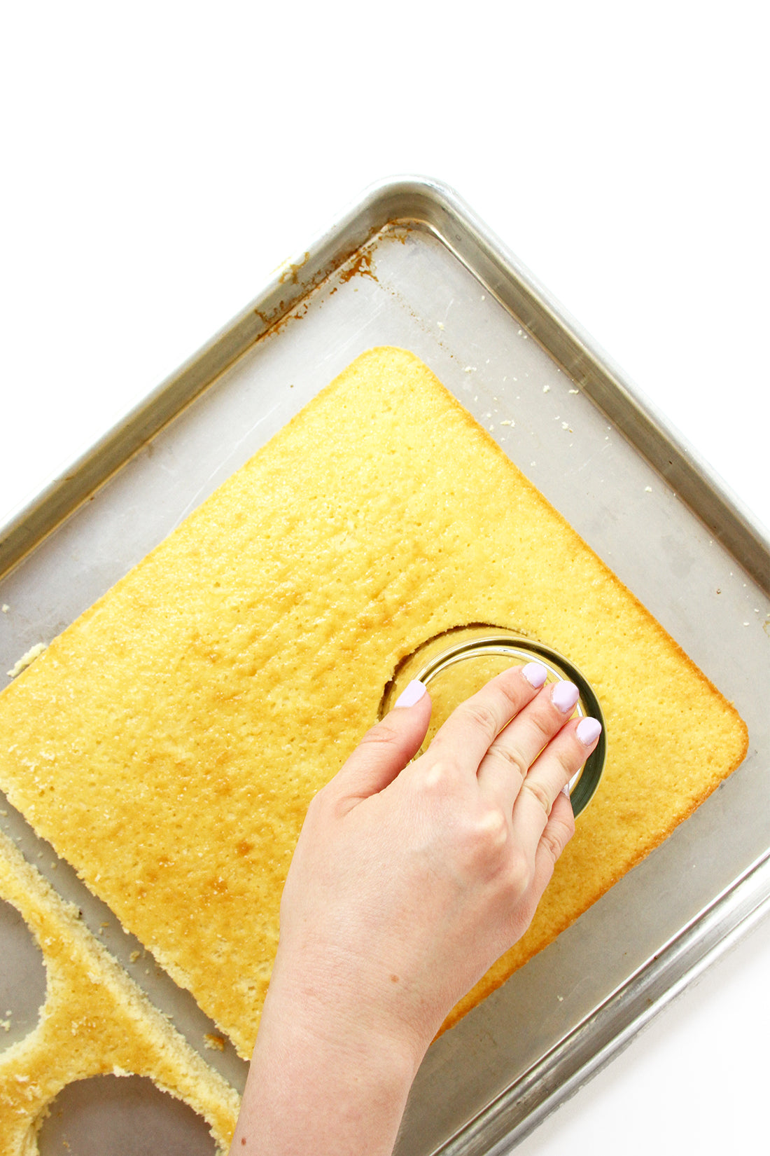 Image from above of a hand cutting out circles from cake on a baking sheet for Miss Jones Baking Co Stone Fruit Shortcake