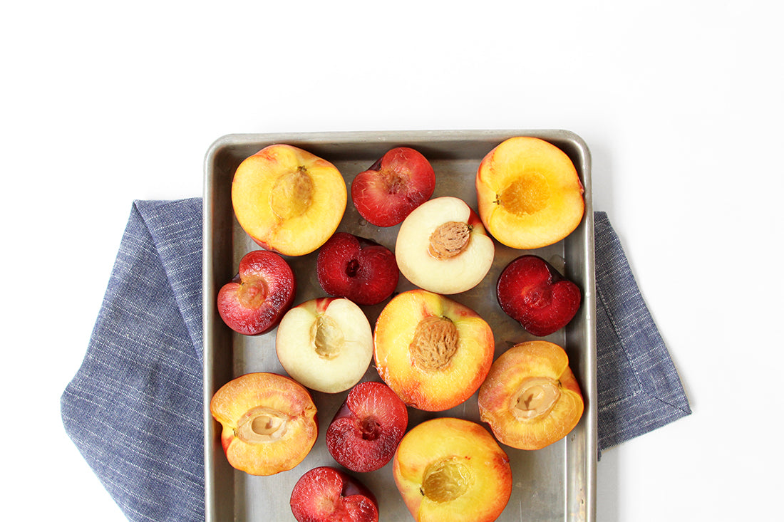 Image from above of halved stone fruits on a baking sheet for Miss Jones Baking Co Stone Fruit Shortcake