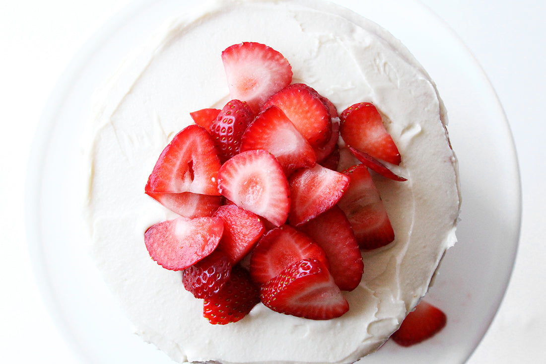 Close up image of top of Miss Jones Baking Co California Strawberry Cake topped with a pile of slices of strawberries.