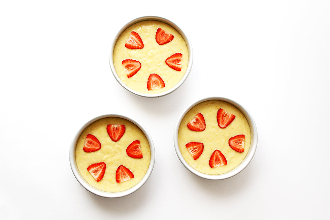 Image from above of three ramekins with batter for Miss Jones Baking Co California Strawberry Cake topped with five slices of strawberries