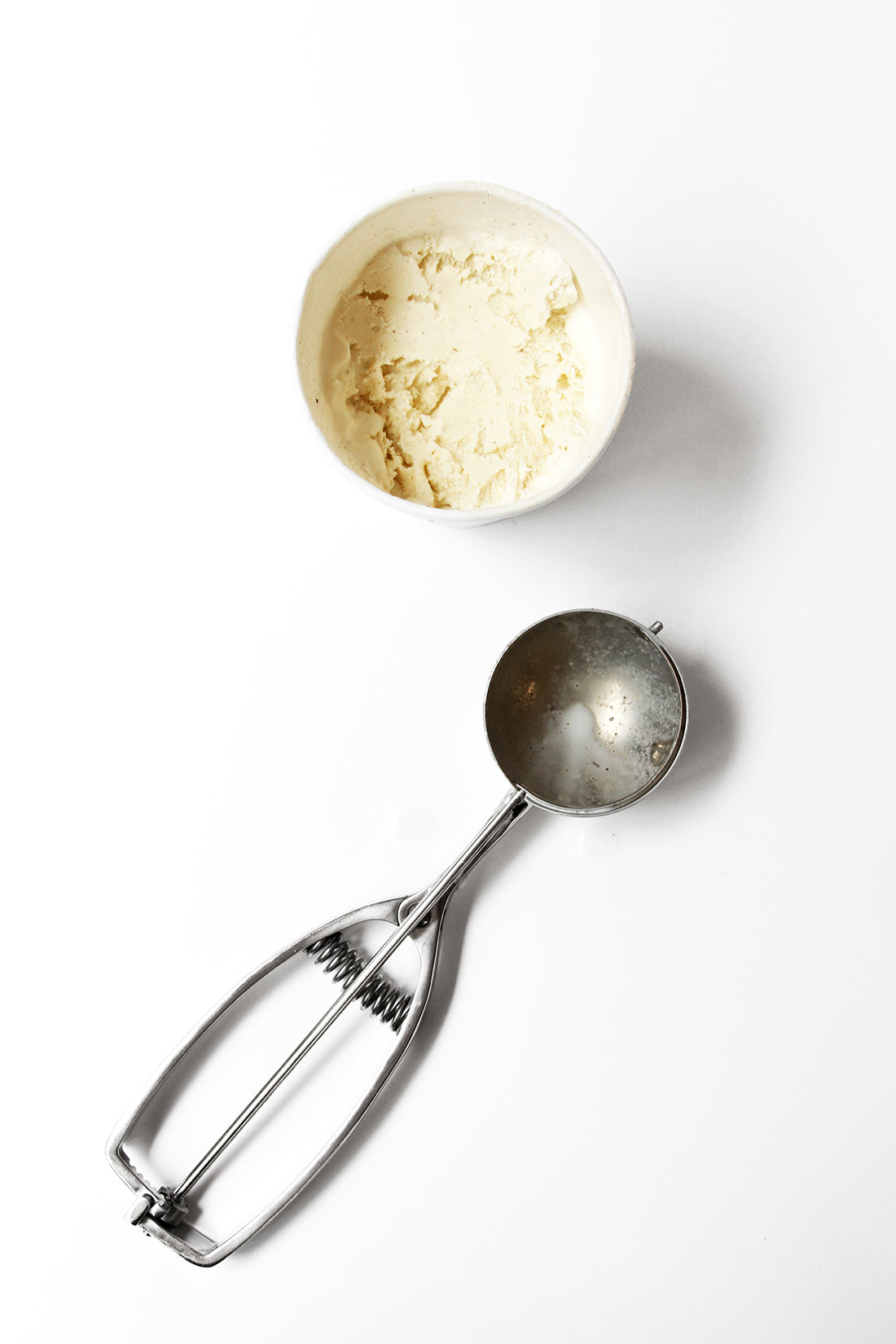 Image from above of a pint of vanilla ice cream next to an ice cream scoop to top Miss Jones Baking Co Summer Strawberry + Rhubarb Tart