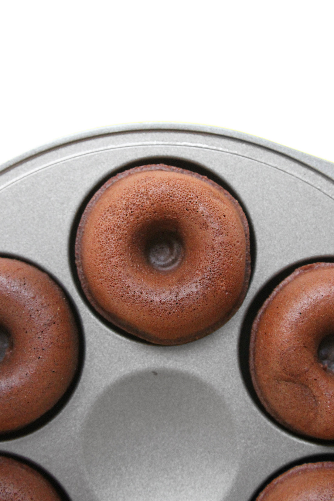 Close up Image of a donut maker with unfrosted Miss Jones Baking Co Thin Mint Donuts