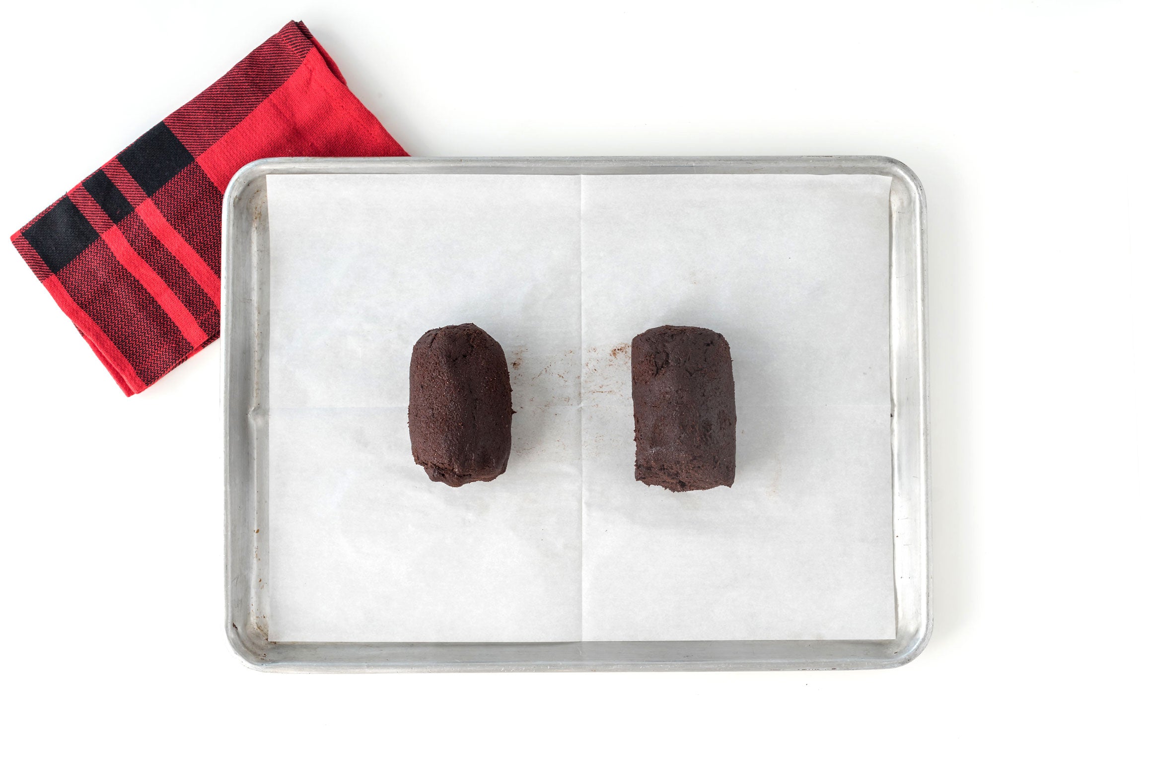 Image of two balls of Miss Jones Baking Co Easy Chocolate Peppermint Cake Mix Biscotti dough on a baking sheet next to a red towel