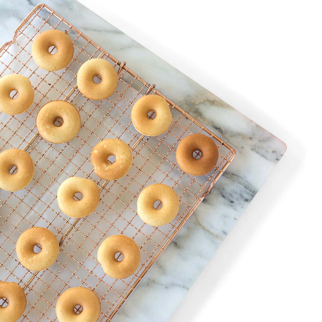 Image of part of a copper baking rack with 14 unglazed Miss Jones Baking Co Easy Holiday Eggnog Mini Donuts