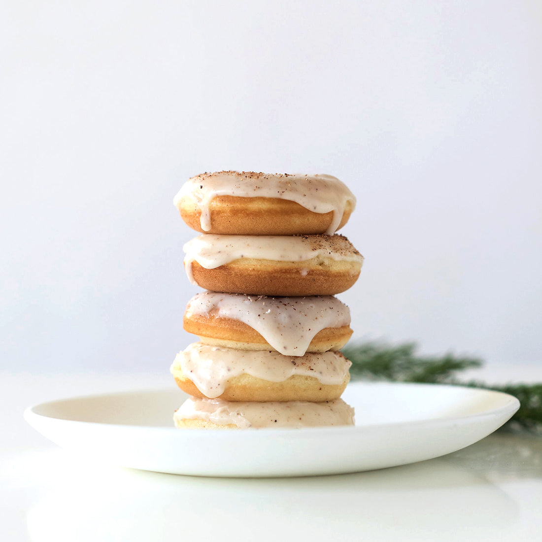 Image of side of five Miss Jones Baking Co Easy Holiday Eggnog Mini Donuts stacked on a white plate