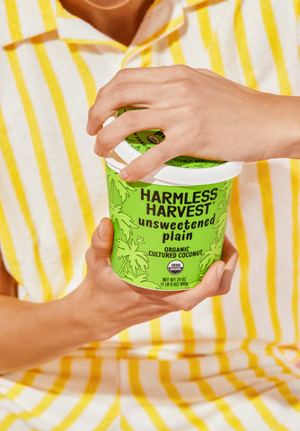 person in yellow striped shirt holding harmless harvest vegan coconut yogurt