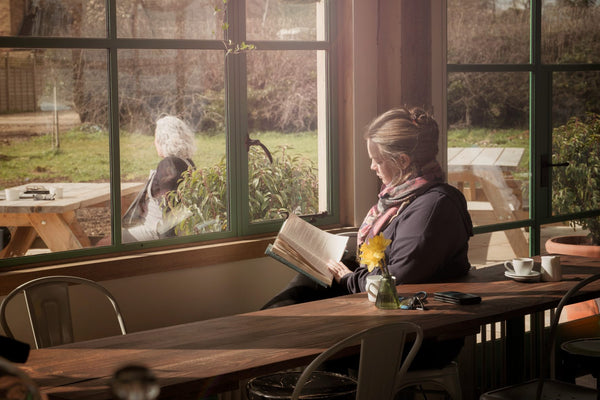 Woman reads book with dog, relaxing in café