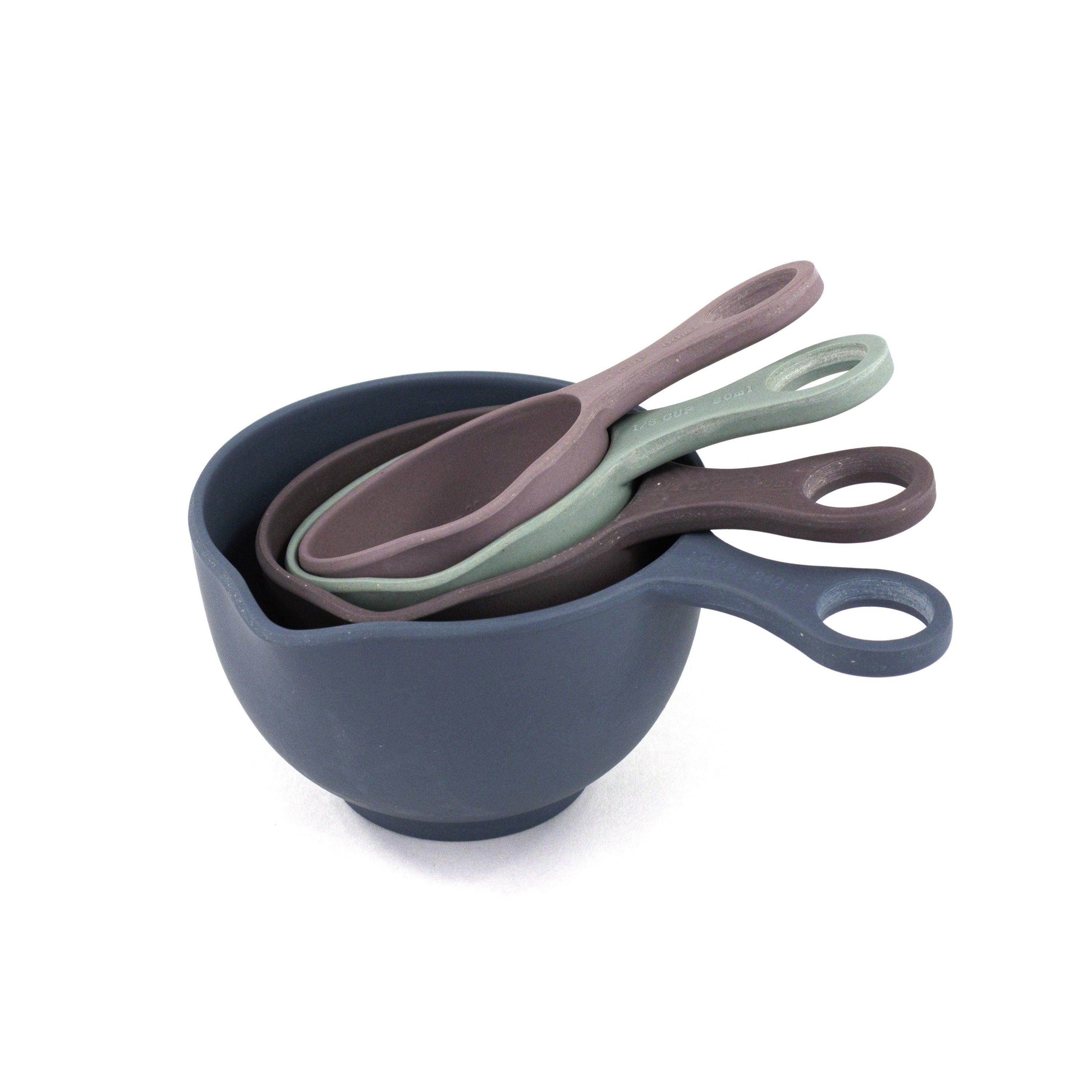 Four measuring cups sit alone in this plain frame. The cups are muted in tone, ranging from blue to mauve to mint green to light purple.